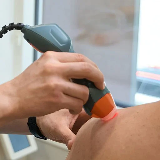 Therapist using laser therapy device on a person's shoulder