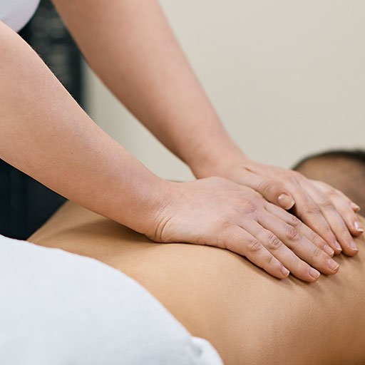 Person receiving a back massage with hands applying pressure on the upper back